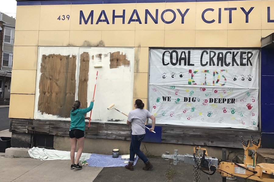 Photo of volunteers using paint rollers to make a visible difference and to help clean up the facade of the Mahanoy City Lumber Company.